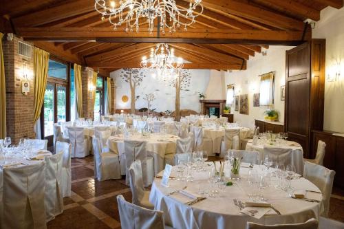 a banquet hall with white tables and chairs and a chandelier at Osteria Alla Pasina in Dosson