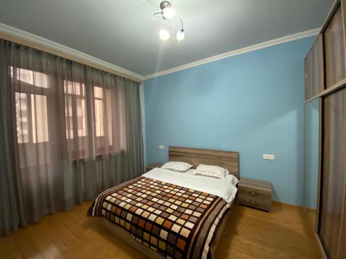 1 dormitorio con cama y pared azul en Argishti street 2 bedroom comfortable apartment in New Building GL933, en Ereván
