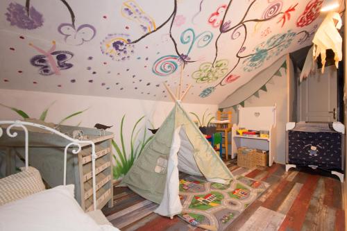 um quarto para crianças com um quarto com uma tenda em Le Gîte du Puit des Granges em Fontaine-sur-Coole