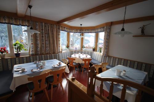 un ristorante con due tavoli, sedie e finestre di Pension Aberger a Saalbach Hinterglemm