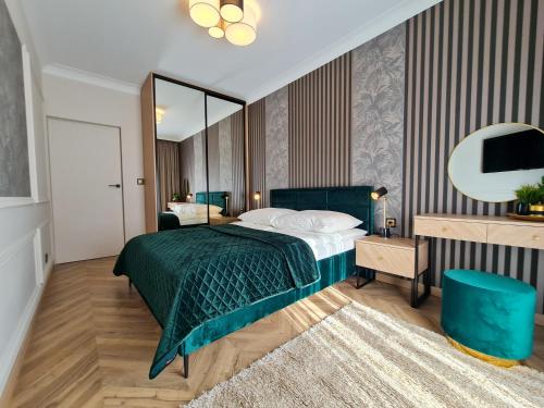 a bedroom with a green bed and a mirror at Apartamenty Hallera 4 in Jarocin
