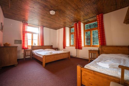 a bedroom with two beds and two windows at Penzion Panský dům in Kvilda