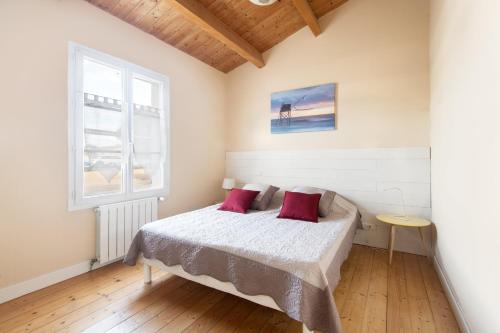 um quarto com uma cama com duas almofadas vermelhas em TETHYS VILLA AVEC PISCINE ET PROCHE DE LA MER em Sainte-Marie-de-Ré