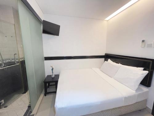 a small bedroom with a white bed and a sink at The Snooze Hotel Marine Parade in Singapore