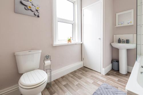 a bathroom with a toilet and a sink and a window at Carnarvon House - Wi-Fi & Parking Contractors in Preston