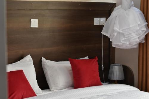 a bedroom with a bed with red and white pillows at Ohm Village Inn(OVI) in Kitui