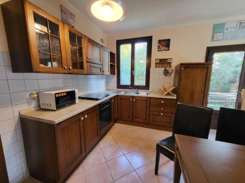 een keuken met houten kasten en een magnetron. bij Mid of Nature ~ Bella Vista sul Lago Maggiore in Ghiffa