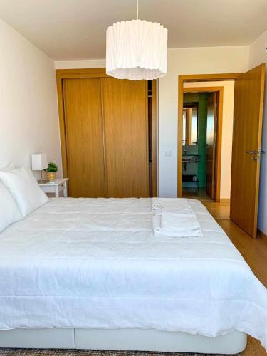 una camera da letto con un grande letto bianco e un lampadario a braccio di Charming Formosa a Cabanas de Tavira