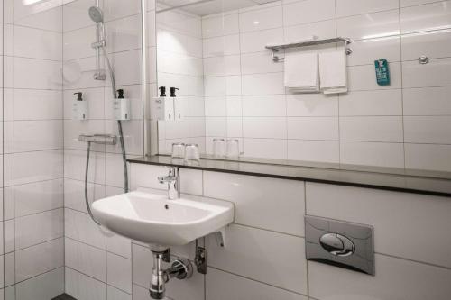uma casa de banho branca com um lavatório e um chuveiro em Scandic Kista em Estocolmo