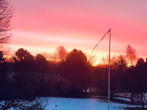 a sunset with a flag pole in a snowy field at The Swiss hut 30 minutes from Copenhagen in Kvistgård