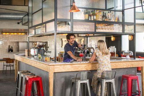 un homme et une femme debout dans un bar dans l'établissement Eklo Bordeaux Centre Bastide, à Bordeaux