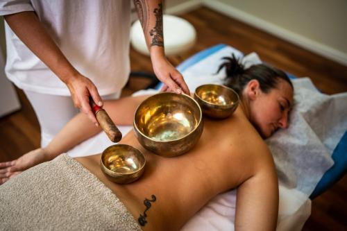 a woman laying in bed with four bowls on her back at Familien- Sportresort BRENNSEEHOF in Feld am See