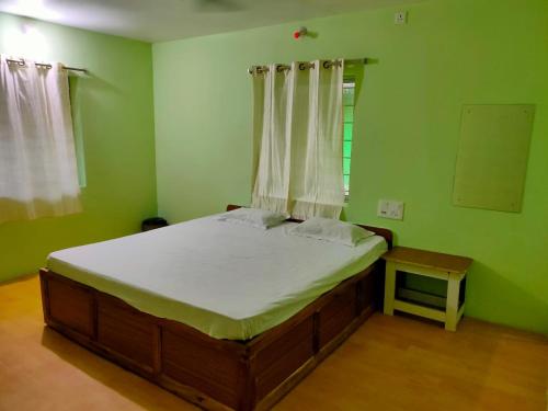 a bedroom with a large bed in a green room at Nature Camp Bhitarkanika Retreat in Righāgarh