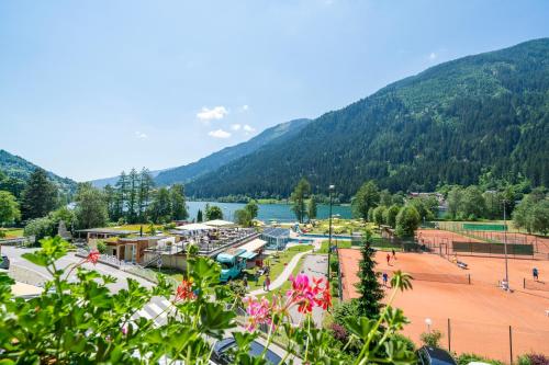 a park with a tennis court in front of a mountain at Familien- Sportresort BRENNSEEHOF in Feld am See