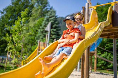 a woman and child riding on a slide at a playground at Familien- Sportresort BRENNSEEHOF in Feld am See
