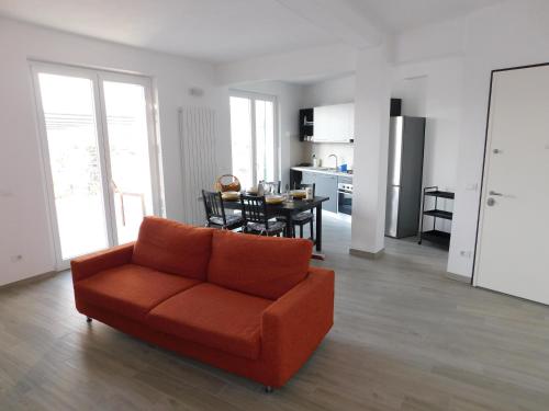 a living room with a orange couch and a kitchen at Quinto Canto Moneglia in Moneglia
