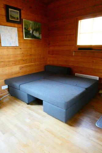 duże niebieskie łóżko w pokoju z drewnianymi ścianami w obiekcie Metsorinne 3A sarvipöllö w mieście Kotila