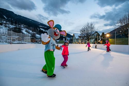 a group of children skating on an ice rink with a mickey mouse at Familien- Sportresort BRENNSEEHOF in Feld am See