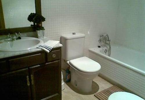 a bathroom with a toilet and a sink and a tub at 2 bed apartment with pools and spa in Vera