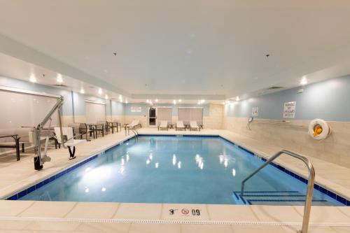 a pool in a hotel with chairs and tables at Holiday Inn Express & Suites - Harrisonburg University Area by IHG in Harrisonburg