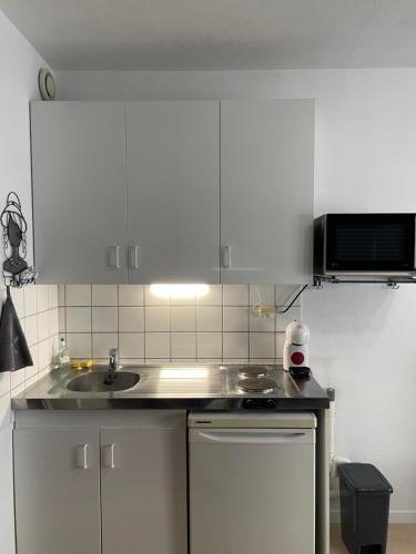 une cuisine avec des armoires blanches et un évier dans l'établissement Studio cosy confortable en centre ville, à Verdun-sur-Meuse