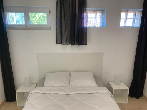 1 dormitorio con 1 cama blanca y 2 ventanas en T2 Climatisé A 20 mètres de la plage en Hyères