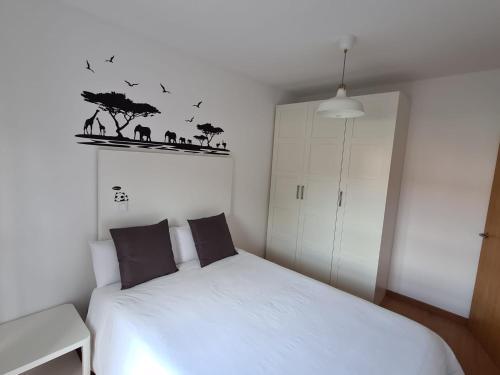 a bedroom with a white bed and a white cabinet at La casita de voto in Bádames
