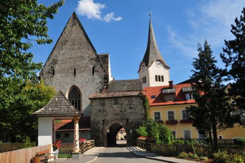 an old building with a gate and a church at Pension Geissler-Reicher in Oberwölz Stadt