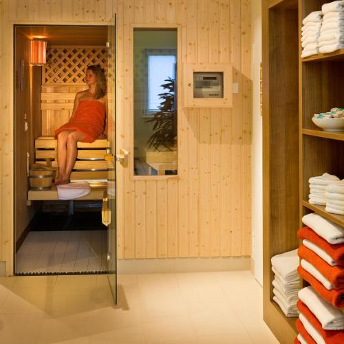 a woman sitting on a bed in a sauna at Mercure Hotel Stuttgart Airport Messe in Stuttgart