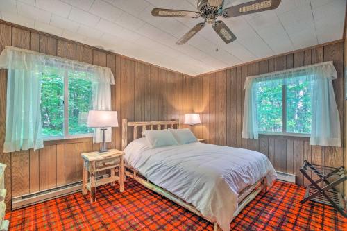 a bedroom with a bed and two windows and a ceiling fan at Cozy Adirondacks Cabin Walk to Lake Eaton! in Jay