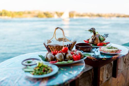 una tavola ricoperta di piatti di cibo accanto all’acqua di Opal privat nubian hotel a Aswan