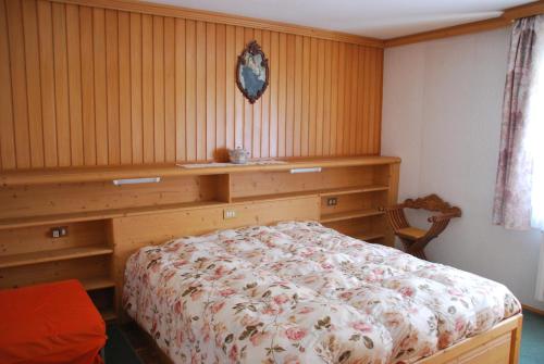 1 dormitorio con 1 cama y pared de madera en Appartamento Anna & Gino, en Sappada