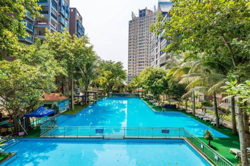 a large swimming pool in a city with palm trees at Doudou Meilan Fengqing Inn in Jinghong