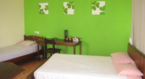 a green room with two beds and a desk at Le cactus guesthouse in Terre Rouge