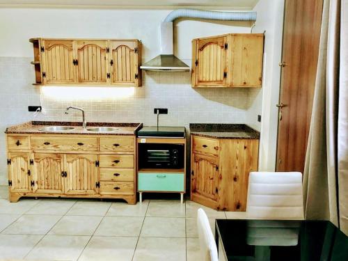 cocina con armarios de madera, fregadero y fogones en Holiday house start point, en Aci Bonaccorsi