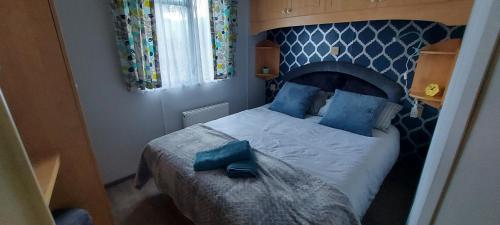 um quarto com uma cama grande e almofadas azuis em Westmorland 32 caravan em Ballantrae