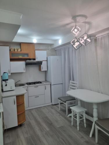 una cocina con electrodomésticos blancos, mesa y sillas en White apartament, en Kremenchuk
