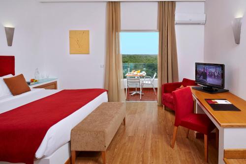 um quarto de hotel com uma cama e uma secretária com um computador em Alcazar Hotel & SPA em Monte Gordo