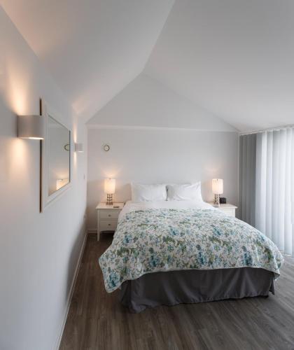 a white bedroom with a large bed and two lamps at Citystay Living - Devonshire Road in Cambridge