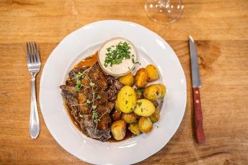 a plate of food with meat and potatoes on a table at Penzion Panský dům in Kvilda
