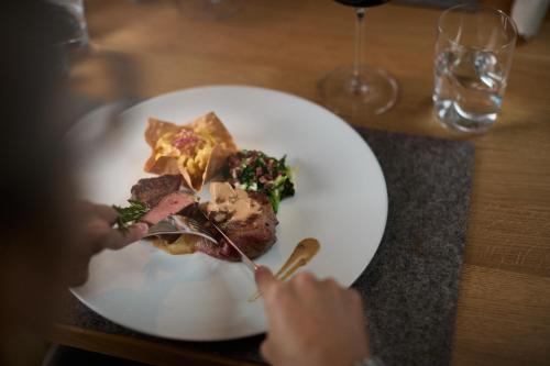 a person eating a plate of food with a fork and knife at Premium Activehotel Bergkönig in Neustift im Stubaital
