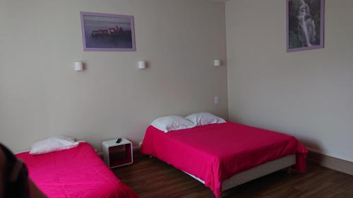 two beds in a room with pink sheets at Hôtel de L'Europe in Gramat