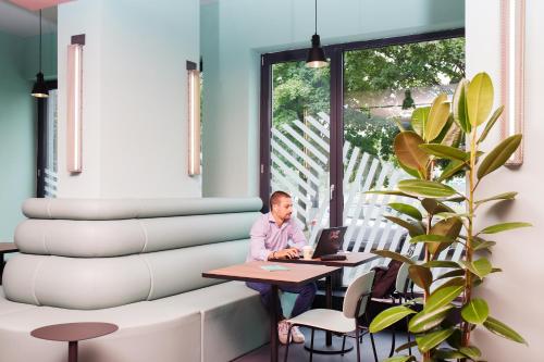 a man sitting at a table with a laptop at CX Turin Vanchiglia in Turin