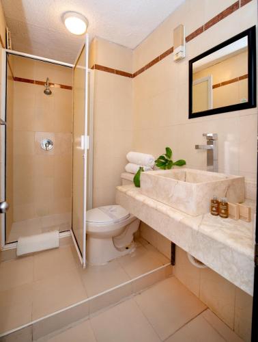 a bathroom with a sink and a toilet and a shower at Oceanfront white sand beach condo for families in Cancún