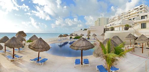a swimming pool with umbrellas and chairs and the ocean at Oceanfront white sand beach condo for families in Cancún