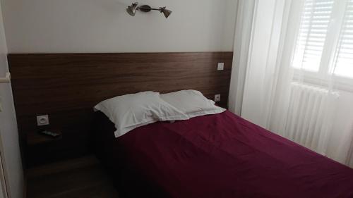 a bedroom with a bed with purple sheets and a window at Hôtel de L'Europe in Gramat