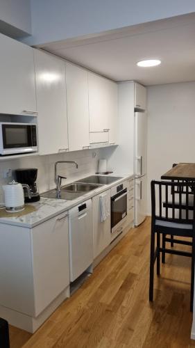 a kitchen with white cabinets and a table with a chair at First Class-Annankatu in Pori