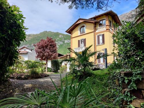 a yellow house with a mountain in the background at Villa Laura in Lierna