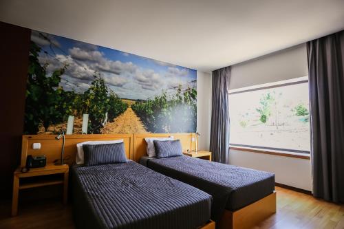Casal CombaにあるBurguezia do Leitãoのベッドルーム1室(ベッド2台付)が備わります。壁には絵画が飾られています。
