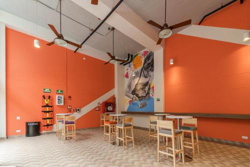 a room with orange walls and tables and chairs at LivinnX Barranquilla in Barranquilla